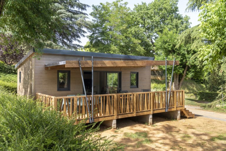 Chalet en bois avec terrasse dans la nature verdoyante.