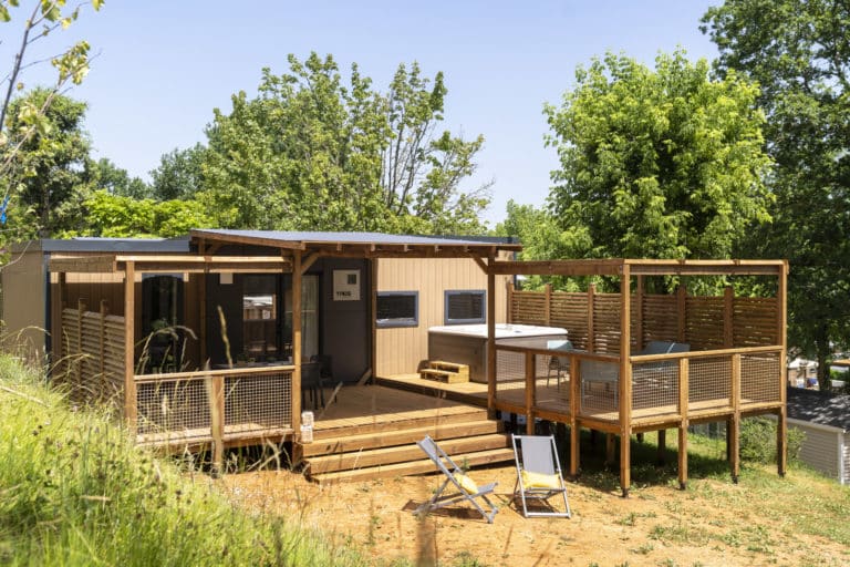 Mobil-home moderne avec terrasse en bois et jacuzzi.