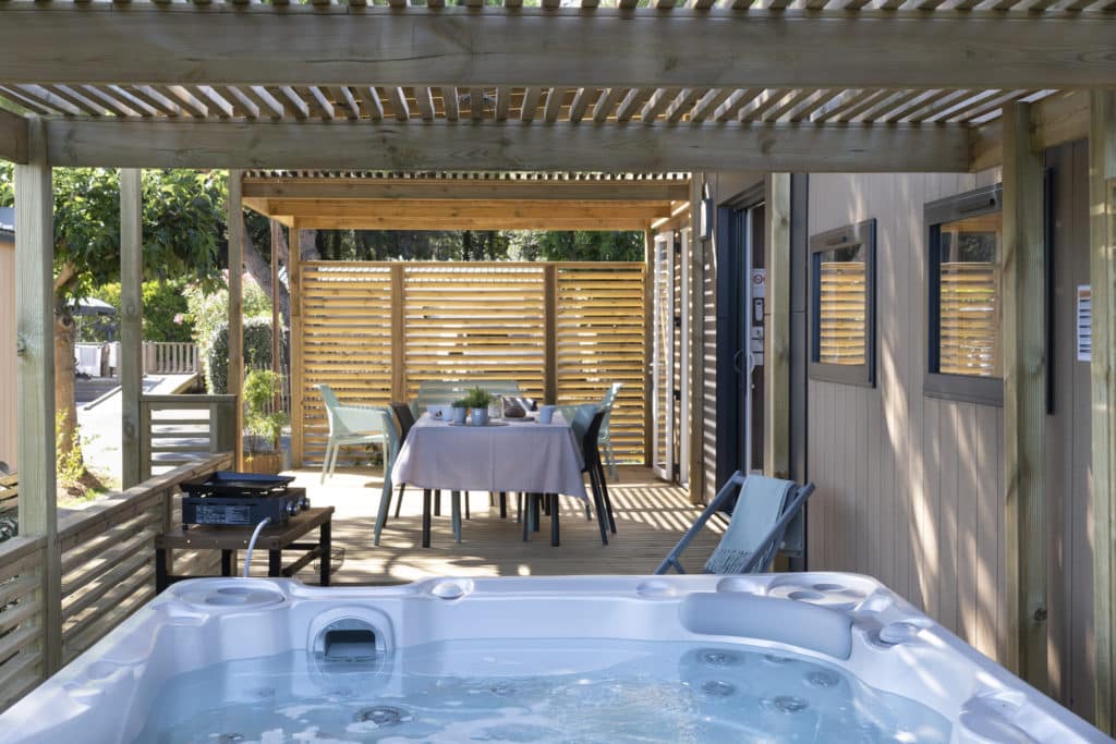 Terrasse avec spa et table à manger extérieure.